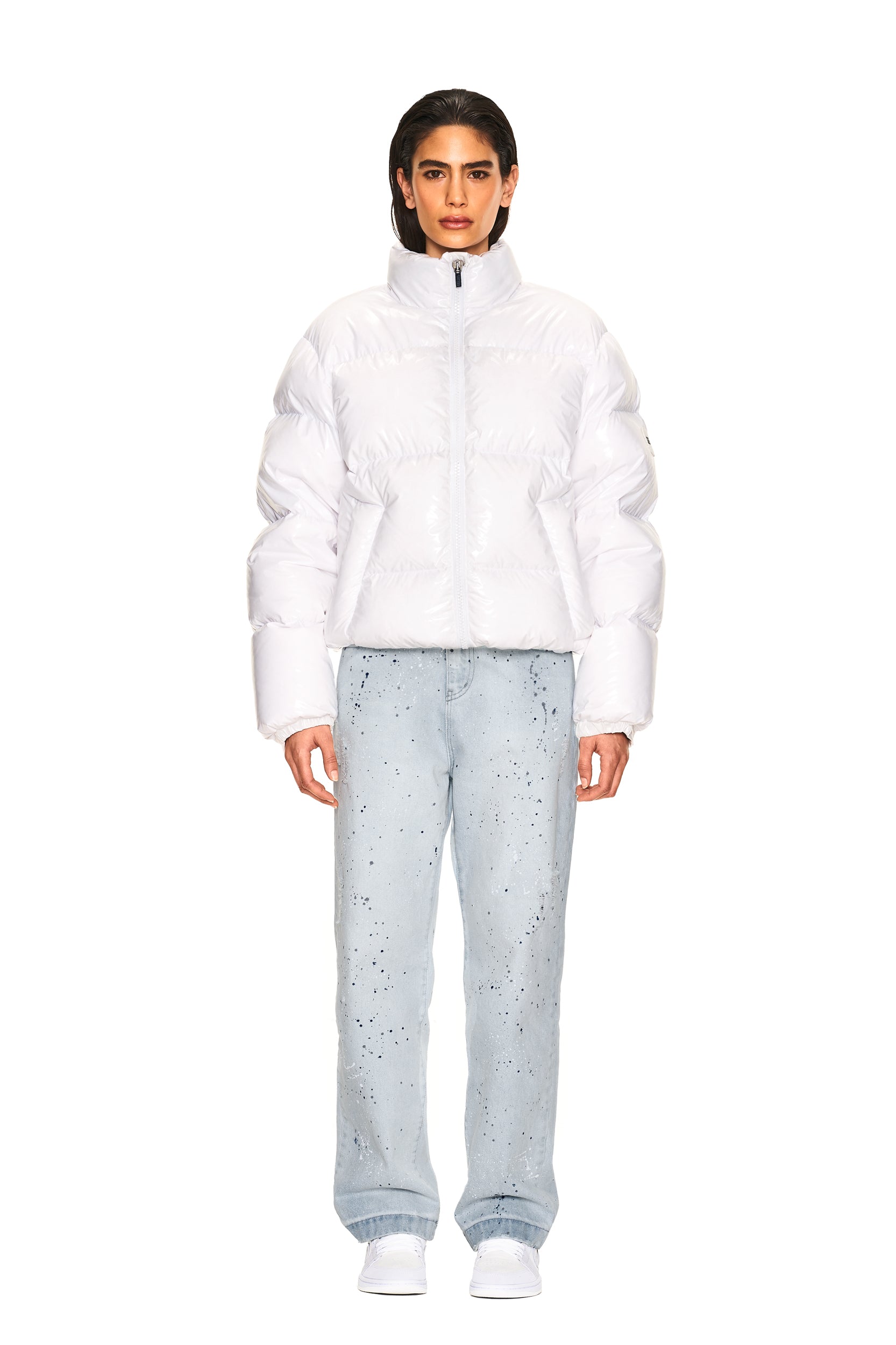 A person faces forward against a plain white background, wearing the 6PM DOWN JACKET WHITE SHINY with light blue speckled jeans and white shoes.