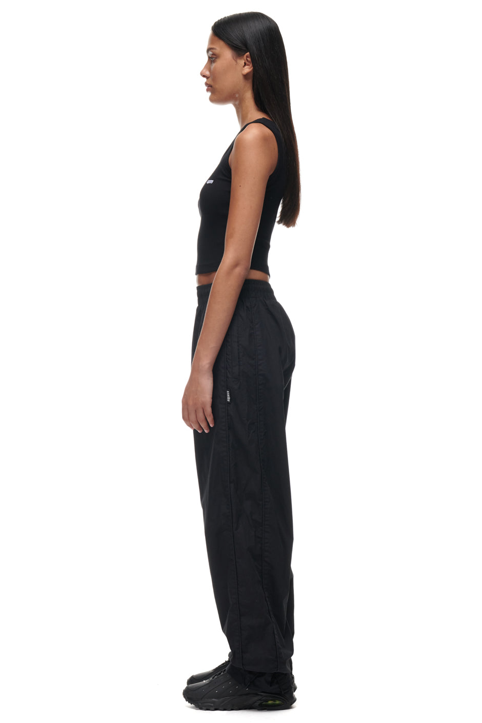 A woman wearing 6PM TRACKPANTS BLACK and a matching black top.