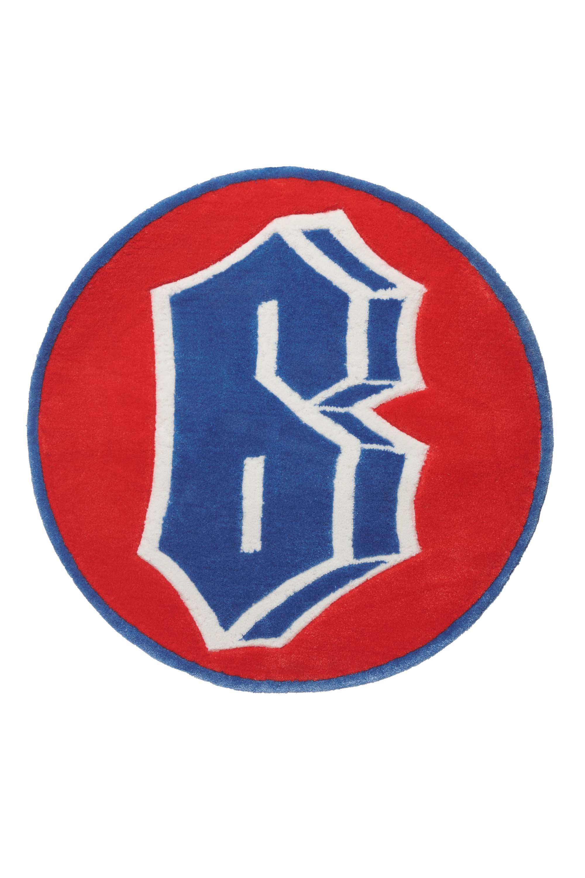 The 6PM CARPET is a round rug featuring a red background, blue border, and a bold blue and white stylized “B” at the center.