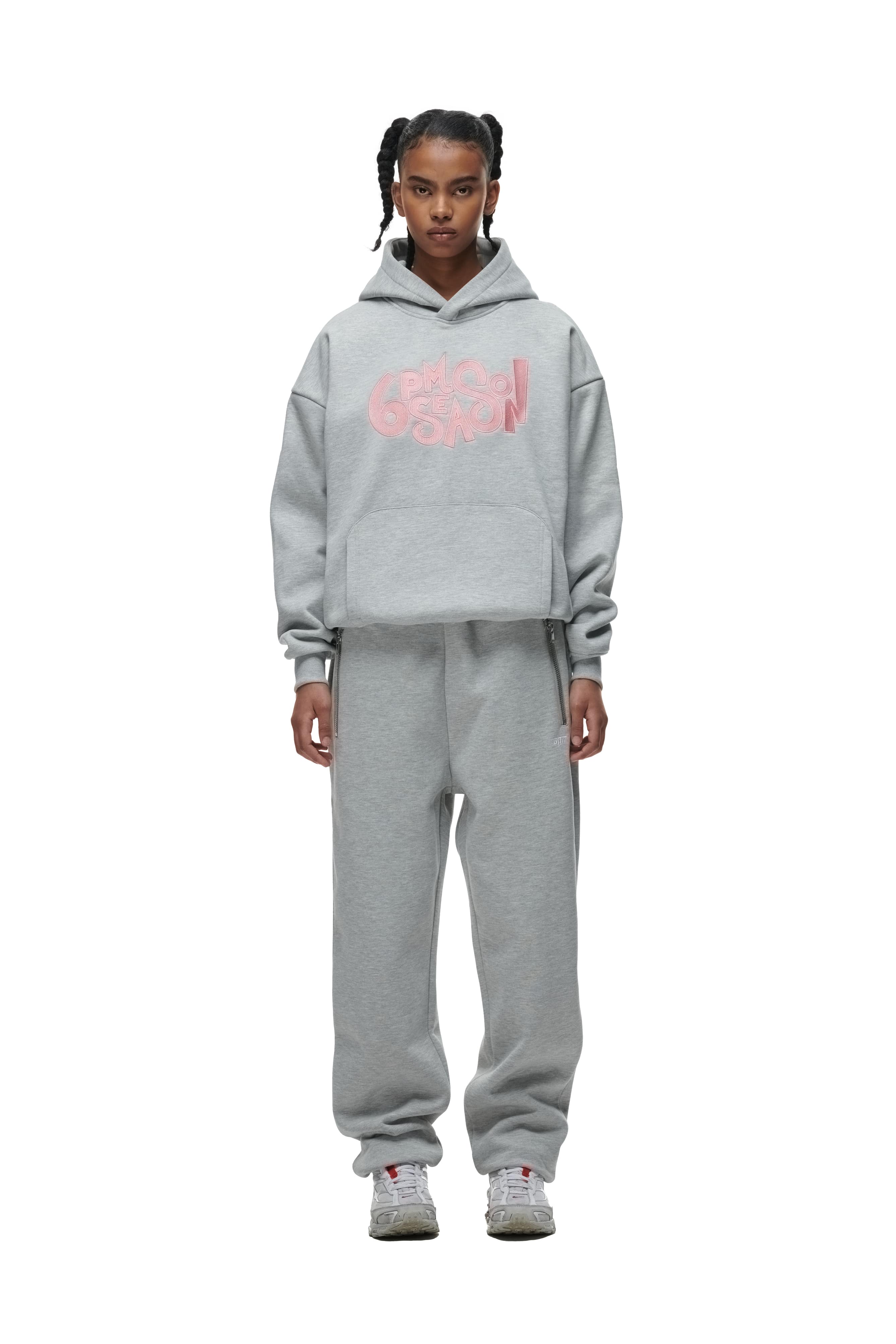 A person stands facing forward wearing the 6PM DOUBLE LAYER PLAY HOODIE GREY, paired with matching grey sweatpants and grey athletic shoes with pink accents.