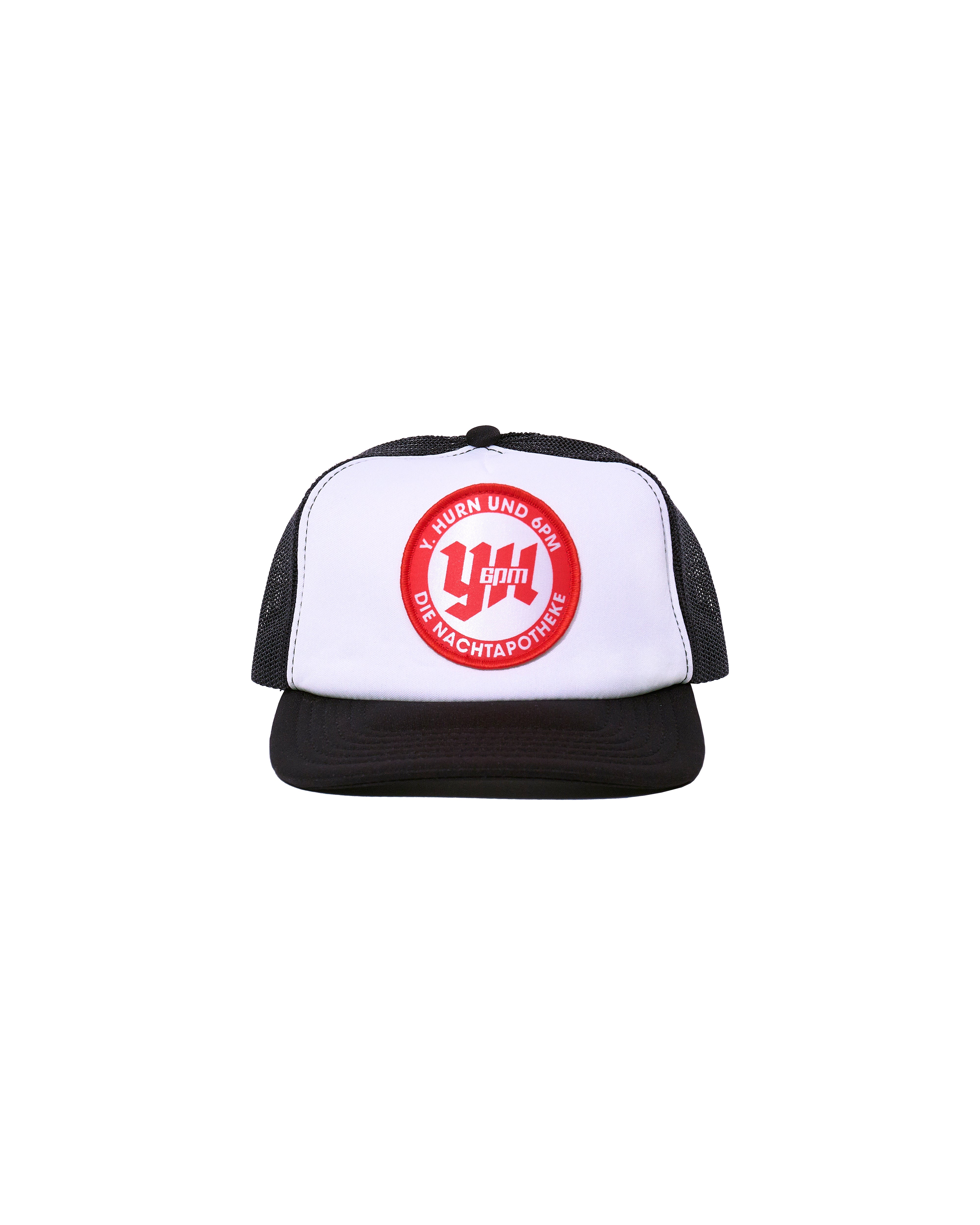 The NACHT AP CAP BLACK by 6PM is a black and white trucker hat featuring a red and white circular front logo with "U-Turn und 50% Die Machtapotheke" text. Set against a plain white background.