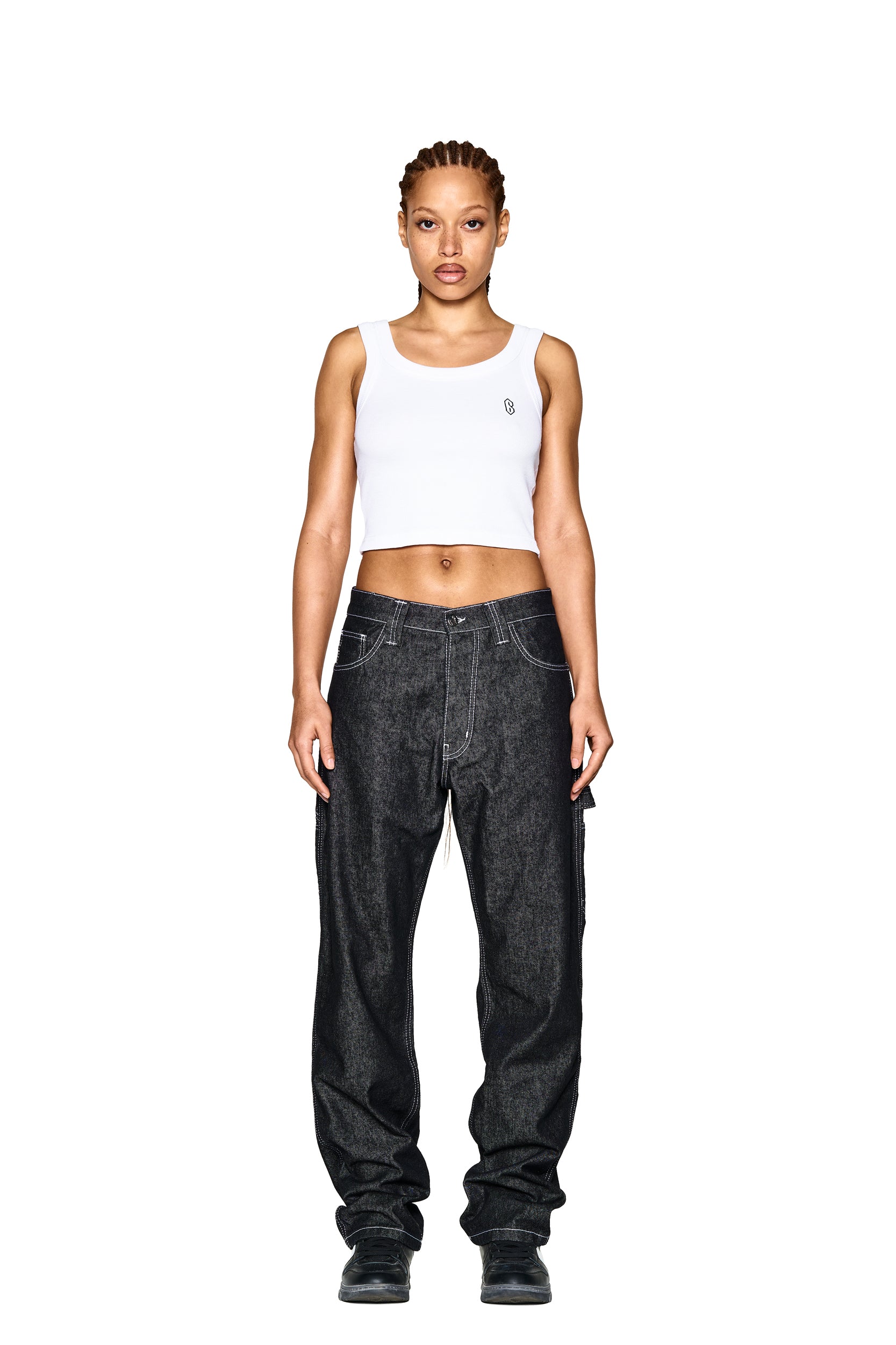 A person stands facing forward, wearing a white crop tank top and 6PM LOGO DENIM JEANS BLACK featuring visible white stitching. The background is plain white.