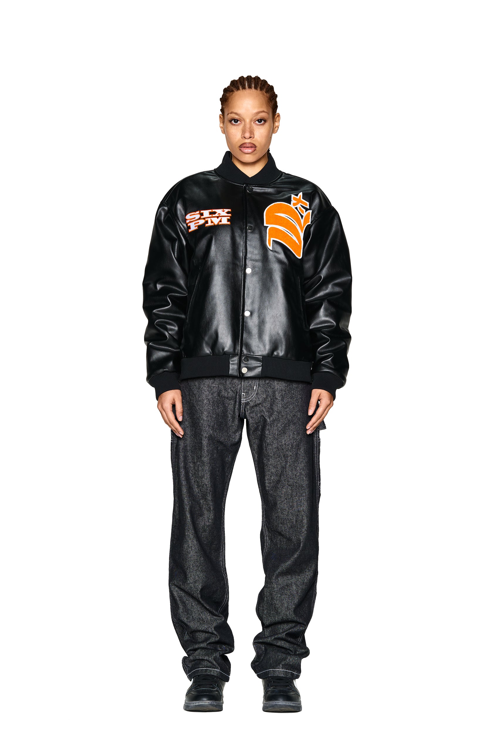 A person stands facing forward against a plain white background, wearing the 6PM COLLEGE JACKET SLAWN BLACK, paired with loose dark jeans and black shoes.