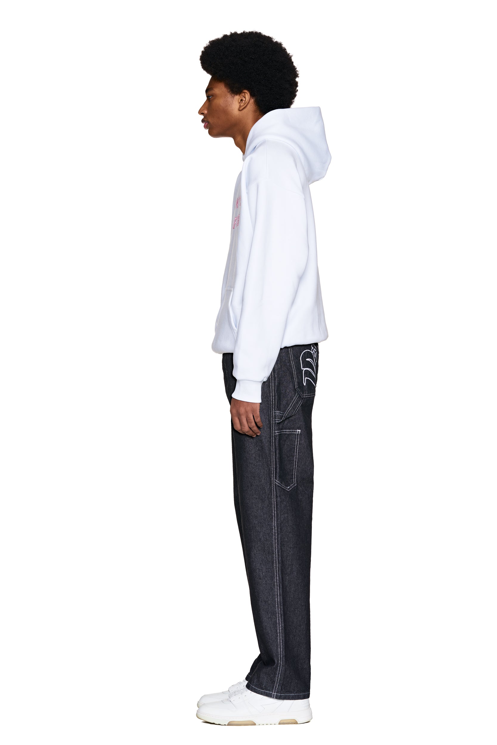 A person in profile wears the 6PM ONLY WEAR AFTER 6PM HOODIE 2.0 WHITE, paired with dark wide-leg jeans featuring visible stitching and white sneakers, set against a plain white background.