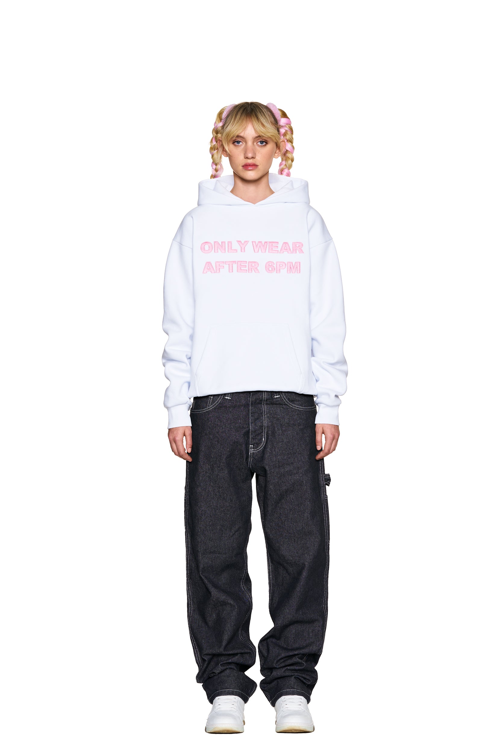 A person with blonde pigtails stands facing forward against a white background, wearing the 6PM ONLY WEAR AFTER 6PM HOODIE 2.0 WHITE, loose dark jeans, and white sneakers.