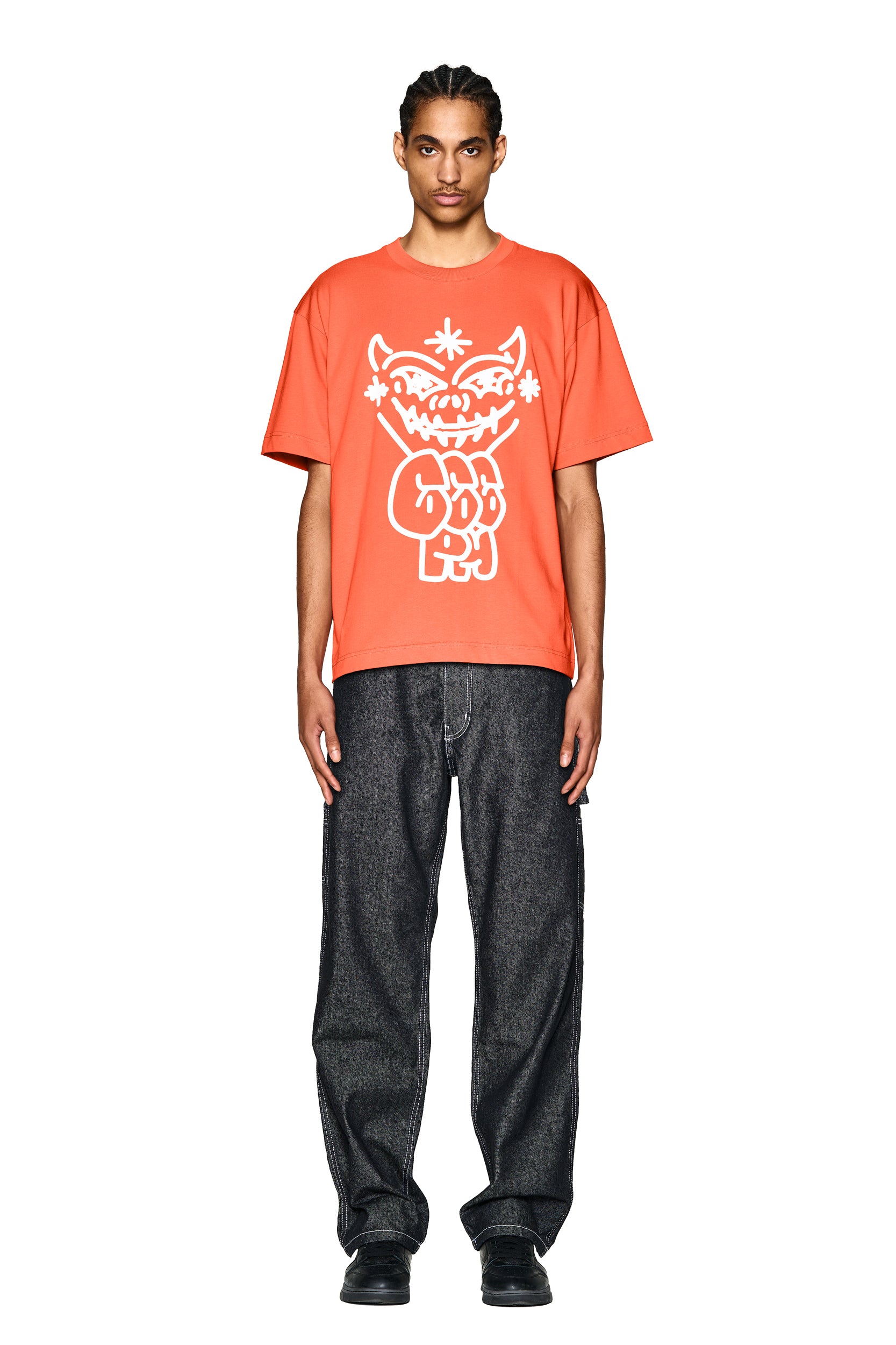 A person stands facing forward, wearing the 6PM DEMON T-SHIRT ORANGE with a bold white graphic, paired with loose dark jeans and black shoes against a white background.