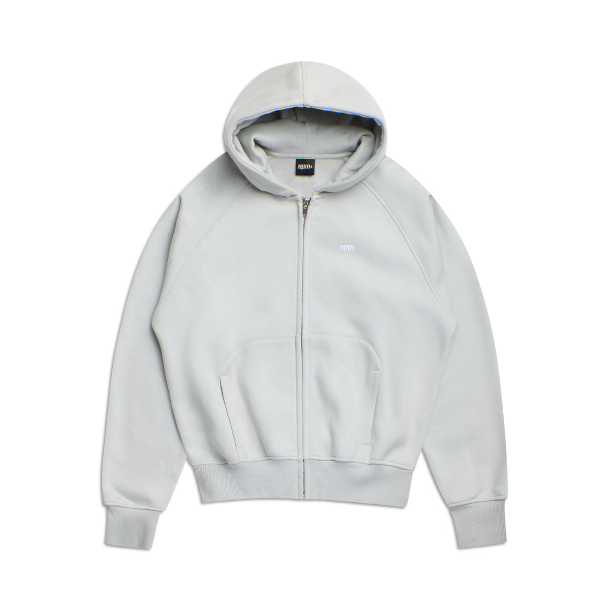 The 6PM ZIP HOODIE SMOKE GREY features a light gray color, zip front, ribbed cuffs and hem, front pocket, and a small white embroidered logo on the left chest. Its structured feel and clean finish suit everyday wear. Shown laid flat on a white background.