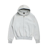 The 6PM ZIP HOODIE SMOKE GREY features a light gray color, zip front, ribbed cuffs and hem, front pocket, and a small white embroidered logo on the left chest. Its structured feel and clean finish suit everyday wear. Shown laid flat on a white background.