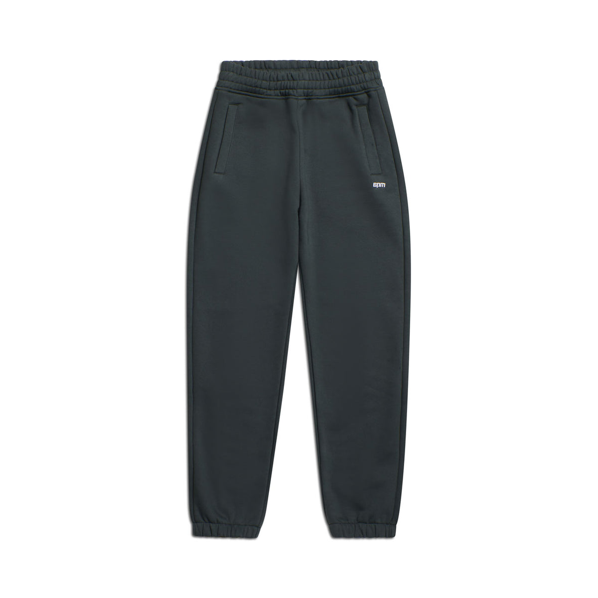 The 6PM CUFF JOGGER DARK EMERALD features an elastic waistband, side pockets, cuffed leg openings, and a small white logo on the upper left thigh. The signature pants are displayed flat against a white background.