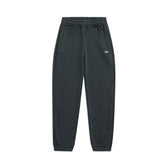 The 6PM CUFF JOGGER DARK EMERALD features an elastic waistband, side pockets, cuffed leg openings, and a small white logo on the upper left thigh. The signature pants are displayed flat against a white background.
