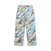 The 6PM DOT CAMO TRACK PANTS feature a wide-leg silhouette and a blue, green, black, and beige pixel camouflage pattern, shown flat against a white background.