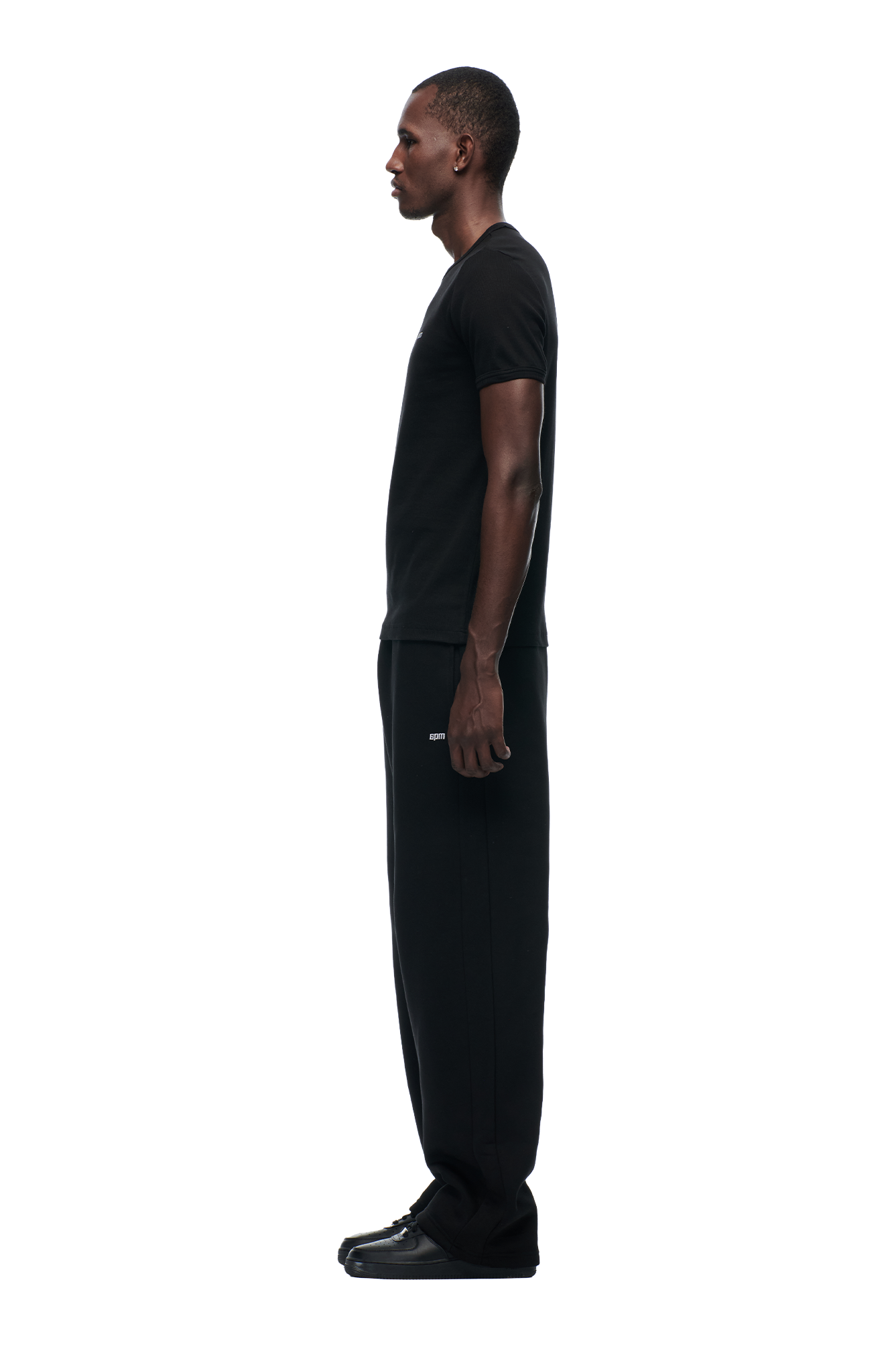 A man is wearing the 6PM RIBBED SLIM FIT TEE BLACK with black pants.