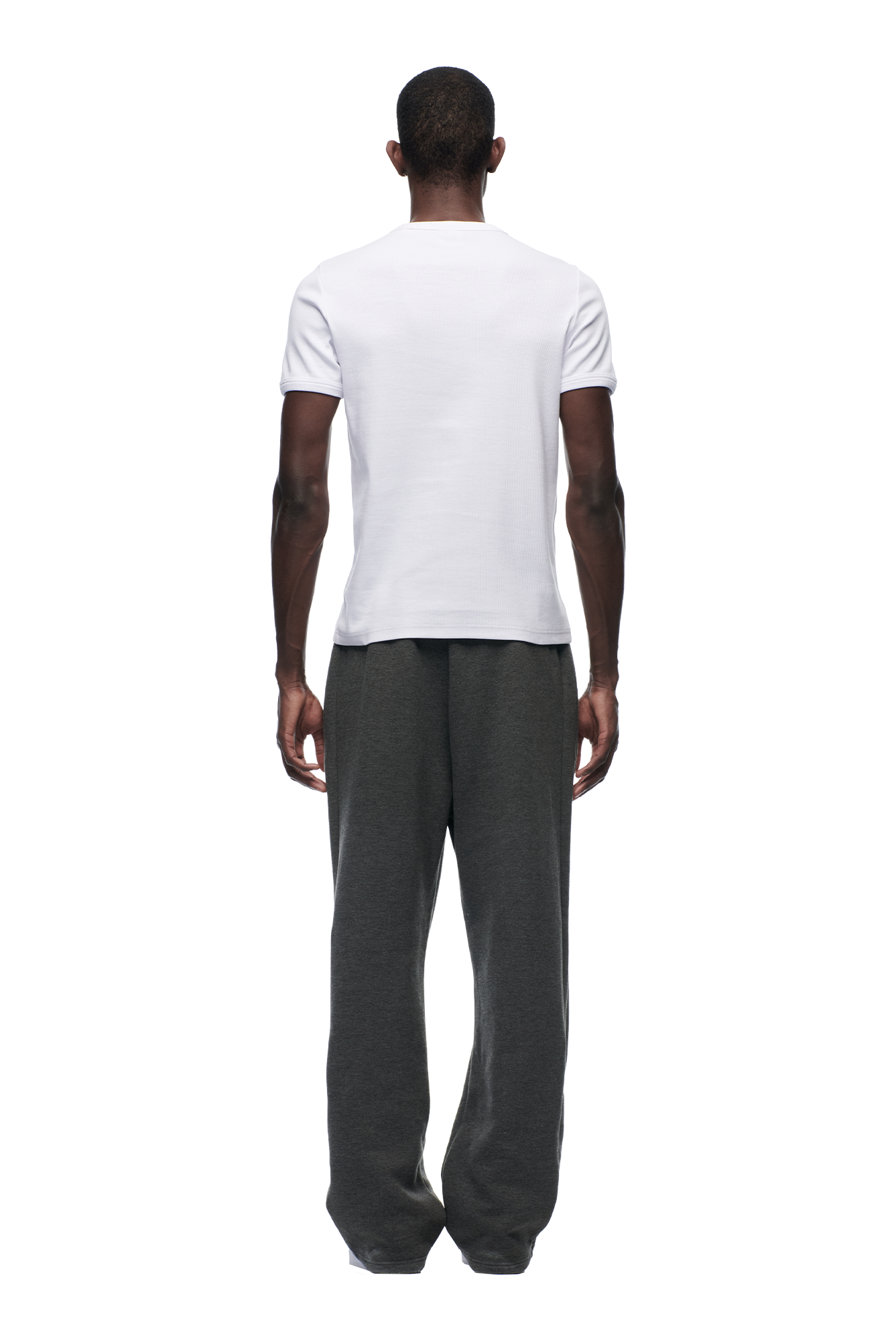 A man faces away, wearing the 6PM RIBBED SLIM FIT TEE in white and loose dark gray pants, set against a white background.
