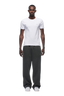 A man faces forward against a plain white background, wearing the 6PM RIBBED SLIM FIT TEE in white, loose dark gray sweatpants, and white sneakers.