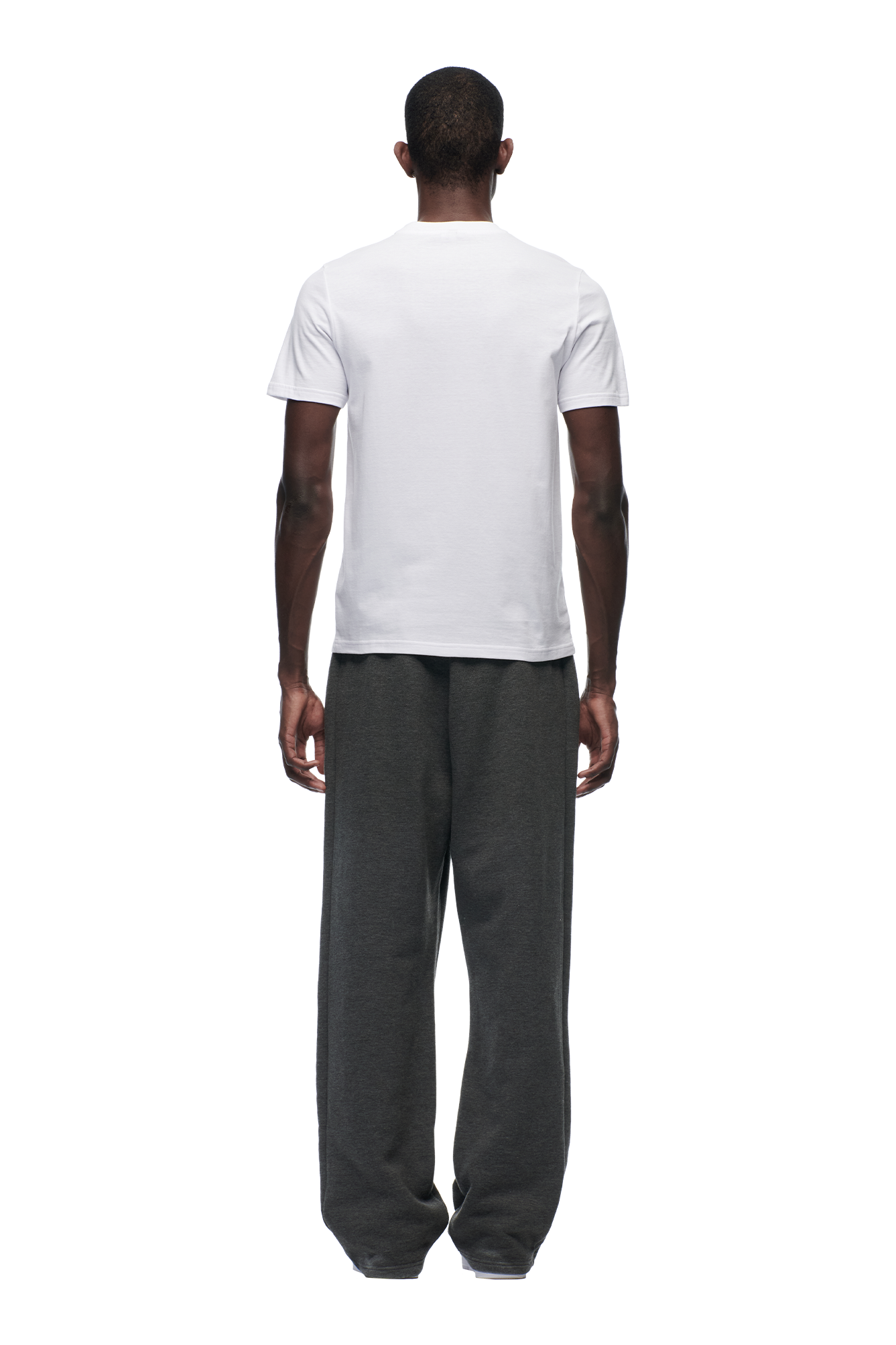 A person stands with their back to the camera, wearing the 6PM SLIM FIT T-SHIRT WHITE and loose-fitting dark gray sweatpants against a white background.