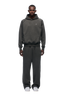 A man stands facing forward against a white background, wearing the 6PM HOODIE DARK GREY MELANGE and matching sweatpants with white sneakers.