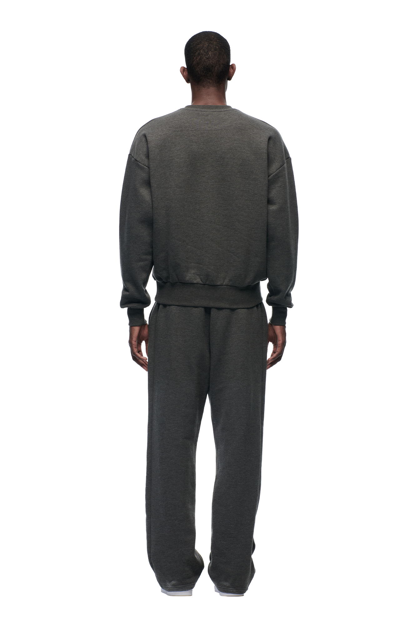 A person faces away from the camera, wearing the 6PM CREWNECK DARK GREY MELANGE sweatshirt with ribbed trims and matching sweatpants, set against a plain white background.