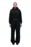 A woman faces forward on a white background, wearing the 6PM WMNS Cropped Hoodie in black, paired with matching black wide-leg sweatpants and black sneakers.