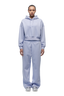 A person faces forward against a white background, wearing the 6PM WMNS CROPPED HOODIE SOFT VIOLET with matching wide-leg sweatpants and silver sneakers.