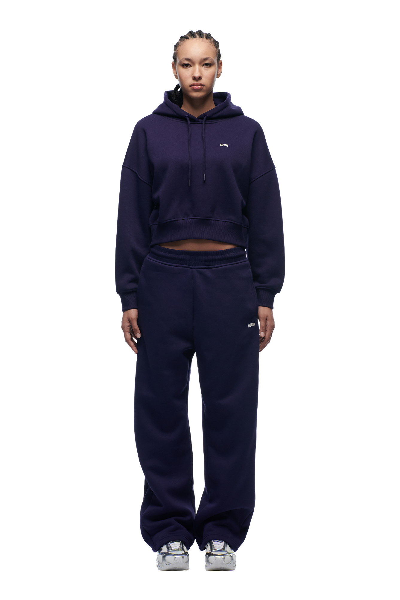 A person faces forward against a plain white background, wearing the 6PM WMNS Cropped Hoodie Orbit Blue with matching loose sweatpants and silver sneakers.