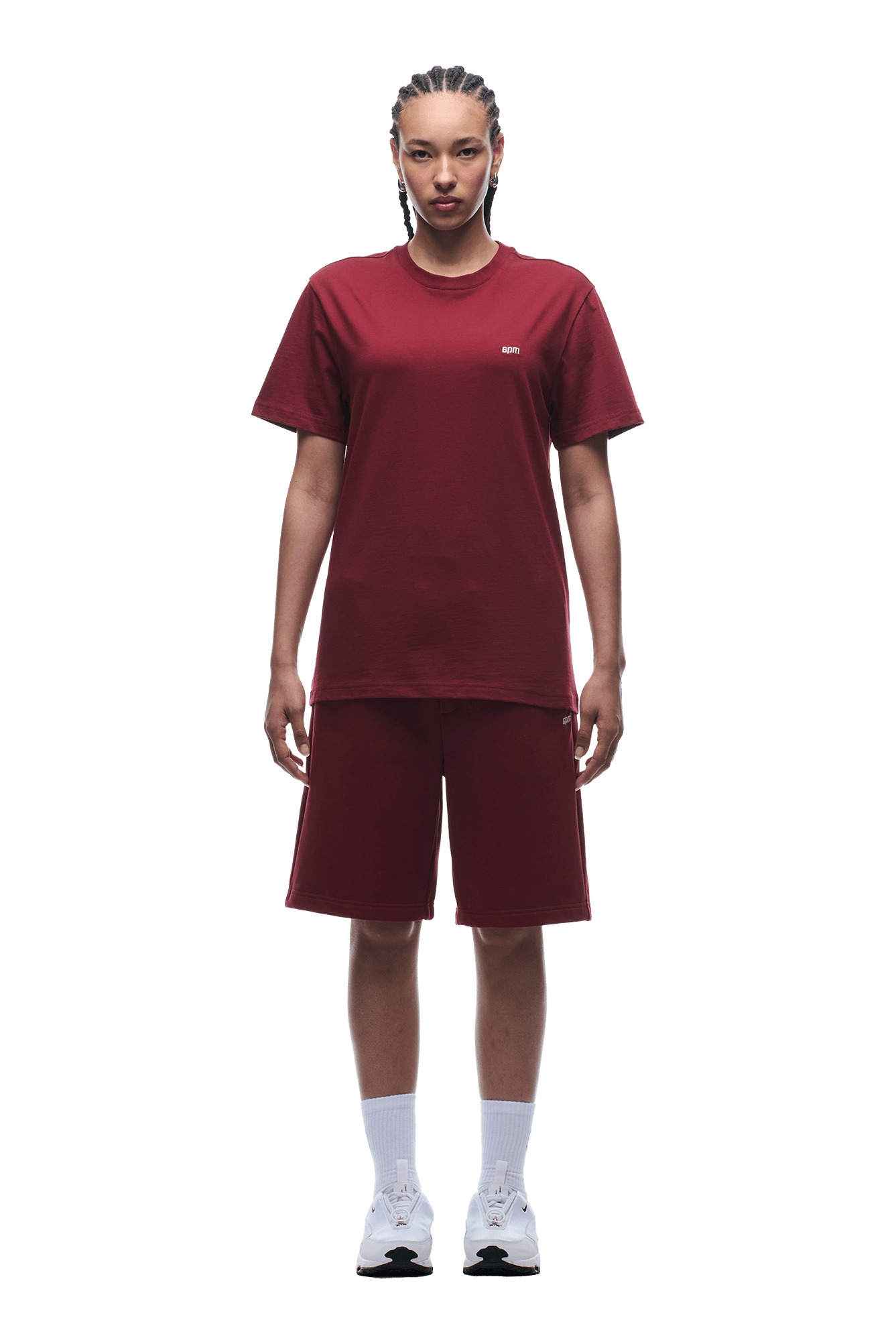 A person stands facing forward in a matching 6PM T-SHIRT REGULAR FIT WINE RED and knee-length shorts, paired with white socks and sneakers, against a transparent background.
