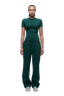 A person stands facing forward, wearing the 6PM WMNS T-SHIRT EVERGREEN with matching drawstring sweatpants and white sneakers against a plain white background.