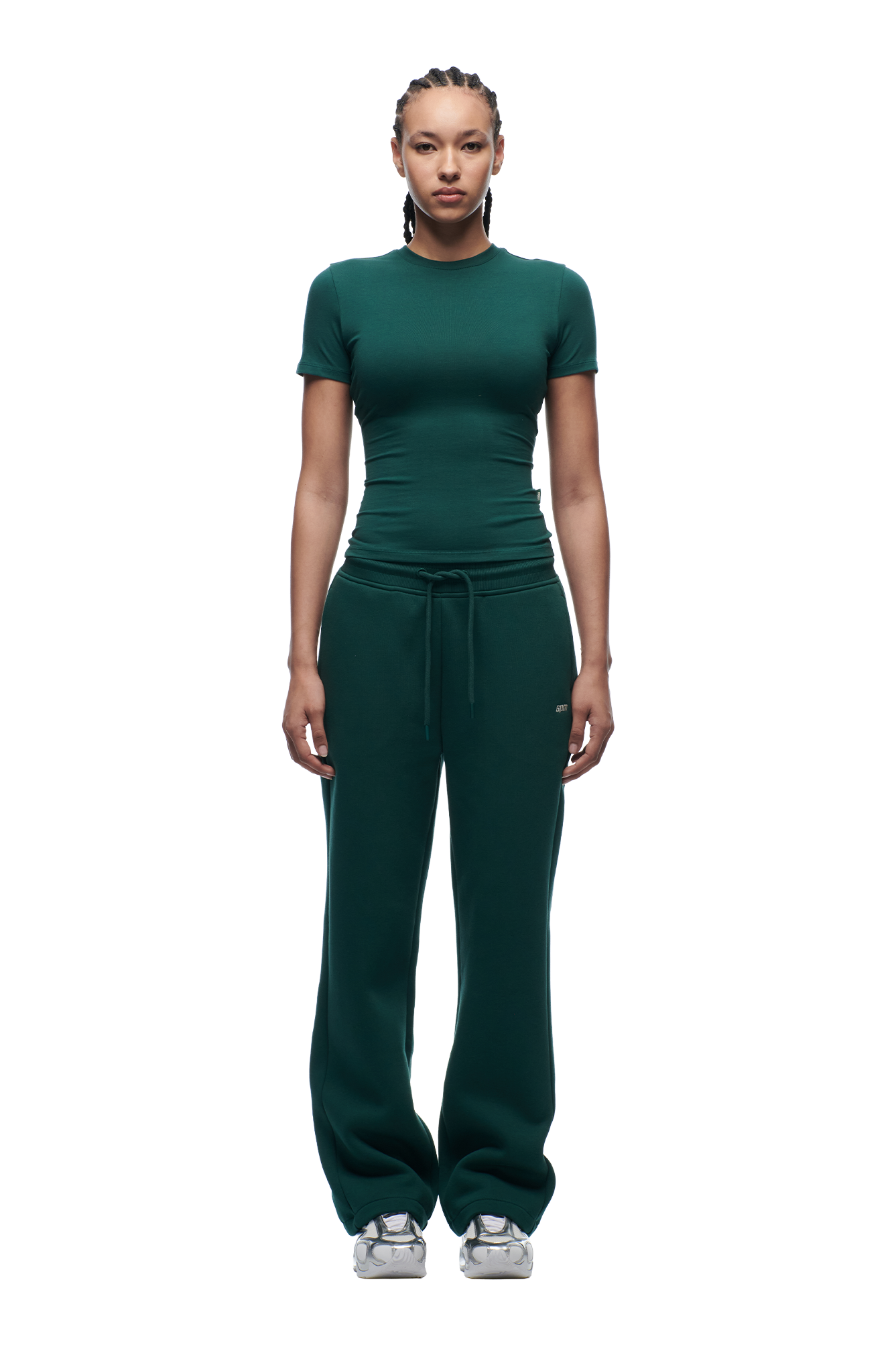 A person stands facing forward, wearing the 6PM WMNS T-SHIRT EVERGREEN with matching drawstring sweatpants and white sneakers against a plain white background.