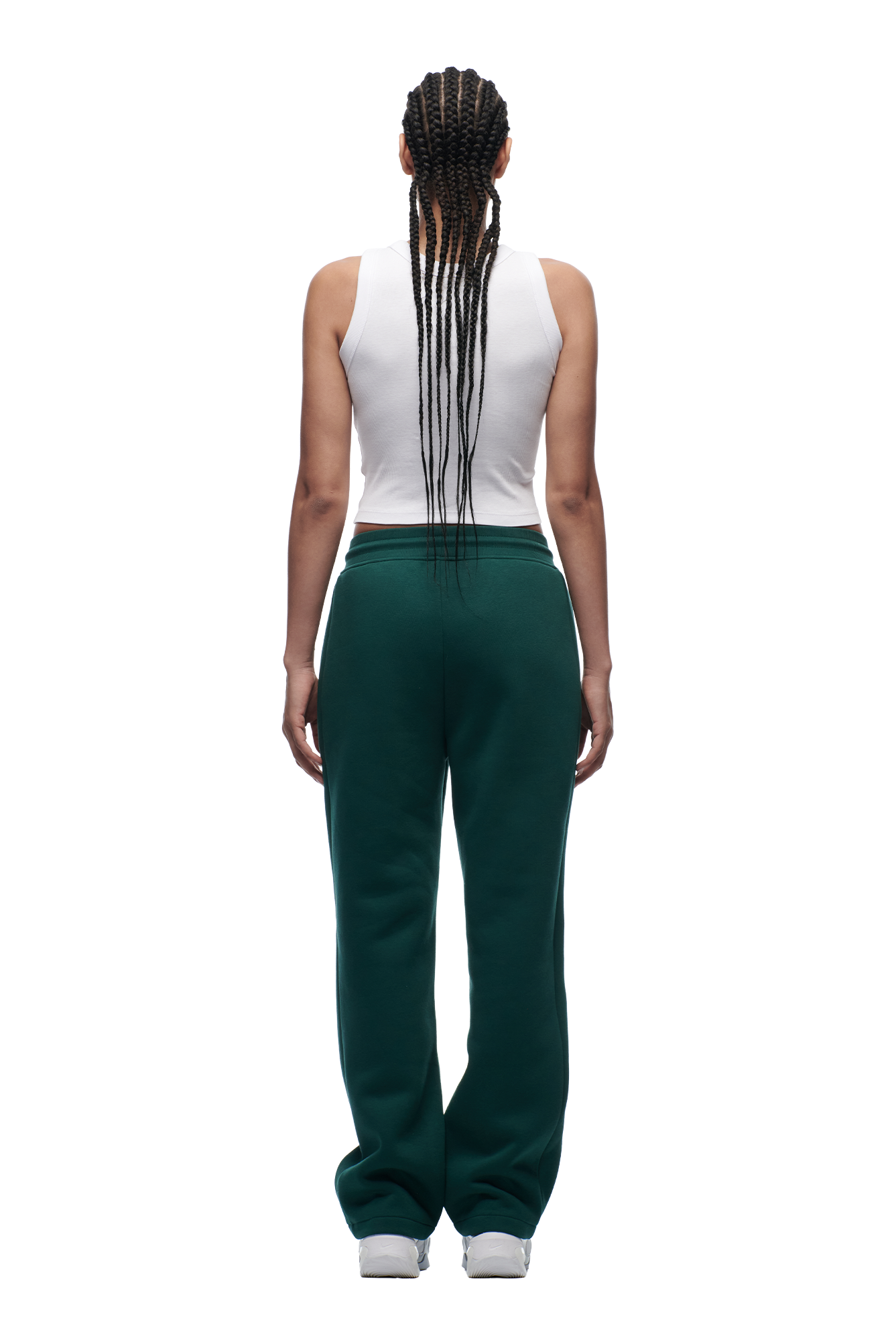 A person with long braids, wearing a white sleeveless top and 6PM WMNS OPEN LEG EVERGREEN sweatpants, stands facing away from the camera against a plain white background.