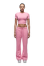A person faces forward against a plain white background, wearing the 6PM WMNS CROPPED T-SHIRT BUBBLEGLOW with loose pink sweatpants and white sneakers.