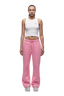 A woman faces forward against a white background, wearing 6PM's WMNS OPEN LEG BUBBLEGLOW pink drawstring sweatpants, a white cropped tank top, and white sneakers.