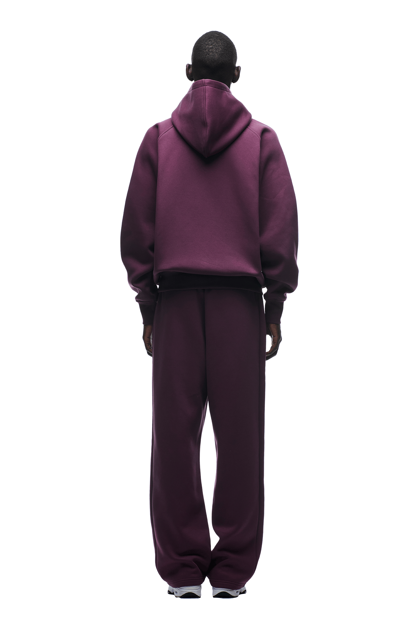A person stands facing away, wearing the 6PM HOODIE PLUM with raglan sleeves and a kangaroo pocket, paired with matching sweatpants and white sneakers. The background is transparent.