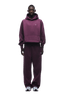 A person faces forward wearing the 6PM HOODIE PLUM, an oversized maroon raglan-sleeved hoodie with a kangaroo pocket and matching sweatpants, paired with white sneakers. The outfit is ideal for everyday wear on a transparent background.