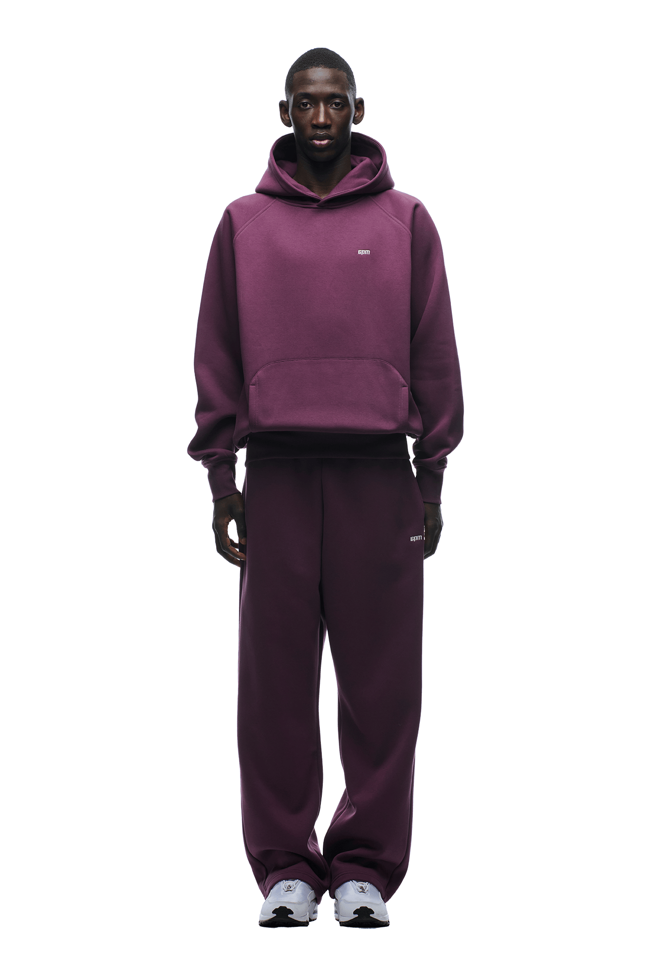 A person faces forward wearing the 6PM HOODIE PLUM, an oversized maroon raglan-sleeved hoodie with a kangaroo pocket and matching sweatpants, paired with white sneakers. The outfit is ideal for everyday wear on a transparent background.