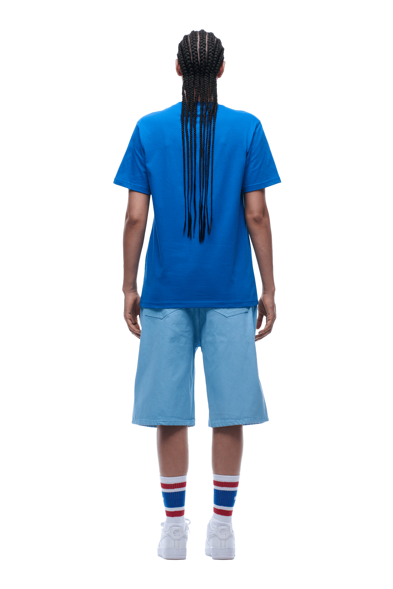 A person with long braids, seen from behind on a transparent background, wears the 6PM APPLE BOY TEE BLUE, light blue knee-length shorts, white sneakers, and white socks featuring blue and red stripes.