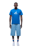 A man faces forward, wearing a blue APPLE BOY TEE BLUE by 6PM, light blue knee-length shorts, striped socks, and white sneakers on a transparent background.