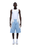 A man stands facing forward in a white sleeveless tank top, 6PM BAGGY WARM UP SHORTS ICE BLUE, white socks, and white sneakers against a plain background.