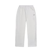 The 6PM OPEN LEG JOGGER COCONUT WHITE features an elastic waistband, side pockets, relaxed fit, and a small logo on the left thigh. Its stacking length enhances the modern classic style. Shown against a plain white background.