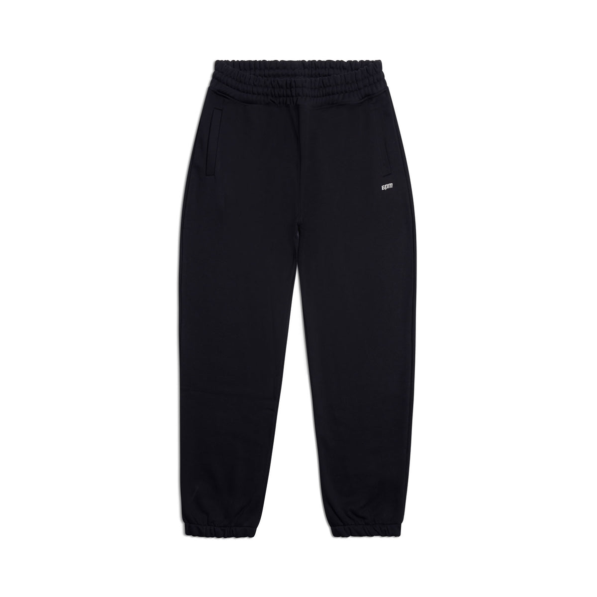 The CUFF JOGGER BLACK features an elastic waistband, cuffed leg openings, two side pockets, and a small white logo on the upper left. These classic black sweatpants are displayed laid flat on a white background.