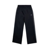 6PM+ NYLON PANTS OPEN LEG BLACK by 6PM: Black nylon track pants with a straight-leg fit, white side stripes, elastic waistband with drawstring, zipped pockets, and small white logo on the upper left thigh. Shown on a plain white background.