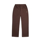 The OPEN LEG JOGGER CHOCOLATE BROWN features an elastic waistband, side pockets, relaxed straight-leg fit, and a small white logo on the left hip. Shown laid flat on a white background for a modern classic look.