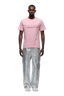 A man faces forward in a 6PM CLEAN EDGE WAVE T-SHIRT PINK with SHERM puff print, silver metallic pants, and white sneakers, set against a plain white background.