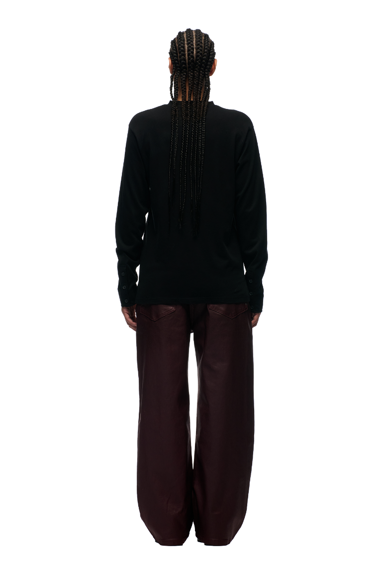 A person with long braids faces away, wearing the 6PM BUTTONED SLIM FIT LS BLACK shirt and loose dark brown pants, set against a plain white background.