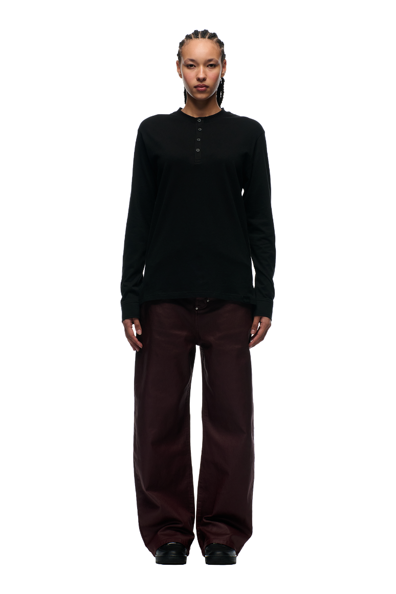 A person with braided hair stands facing forward, wearing the 6PM BUTTONED SLIM FIT LS BLACK shirt with dark brown pants and black shoes, set against a plain white background.