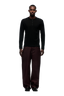 A man faces forward wearing the 6PM BUTTONED SLIM FIT LS BLACK shirt, styled with loose dark brown pants and black shoes, set against a plain light gray background.