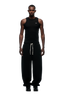 A man stands facing forward in a fitted black tank top and 6PM X-TRA WIDE CUFF JOGGER BLACK pants with white laces, wide cuffs, and black shoes, set against a plain white background.