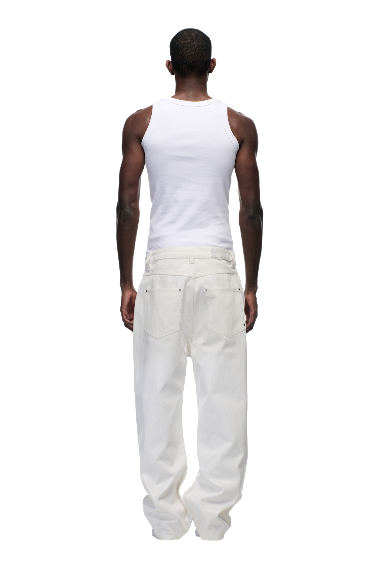 A person faces away, wearing the 6PM WAX COATED DENIM WHITE sleeveless tank top and loose-fit jeans with a leather badge, all against a plain white background.