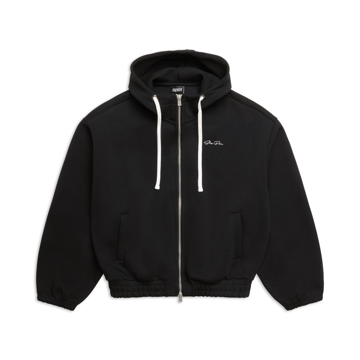 The 6PM BOXY ZIP HOODIE BLACK features white drawstrings, ribbed cuffs and hem, and small white text on the left chest. It is displayed laid flat on a white background.