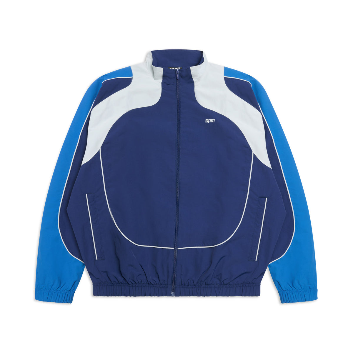 The 6PM EVERYDAY TRACK JACKET SHADOW BLUE is a blue and white track jacket with a front zipper, long sleeves, elastic cuffs and hem, curved white accents, and light blue panels on the shoulders and arms.