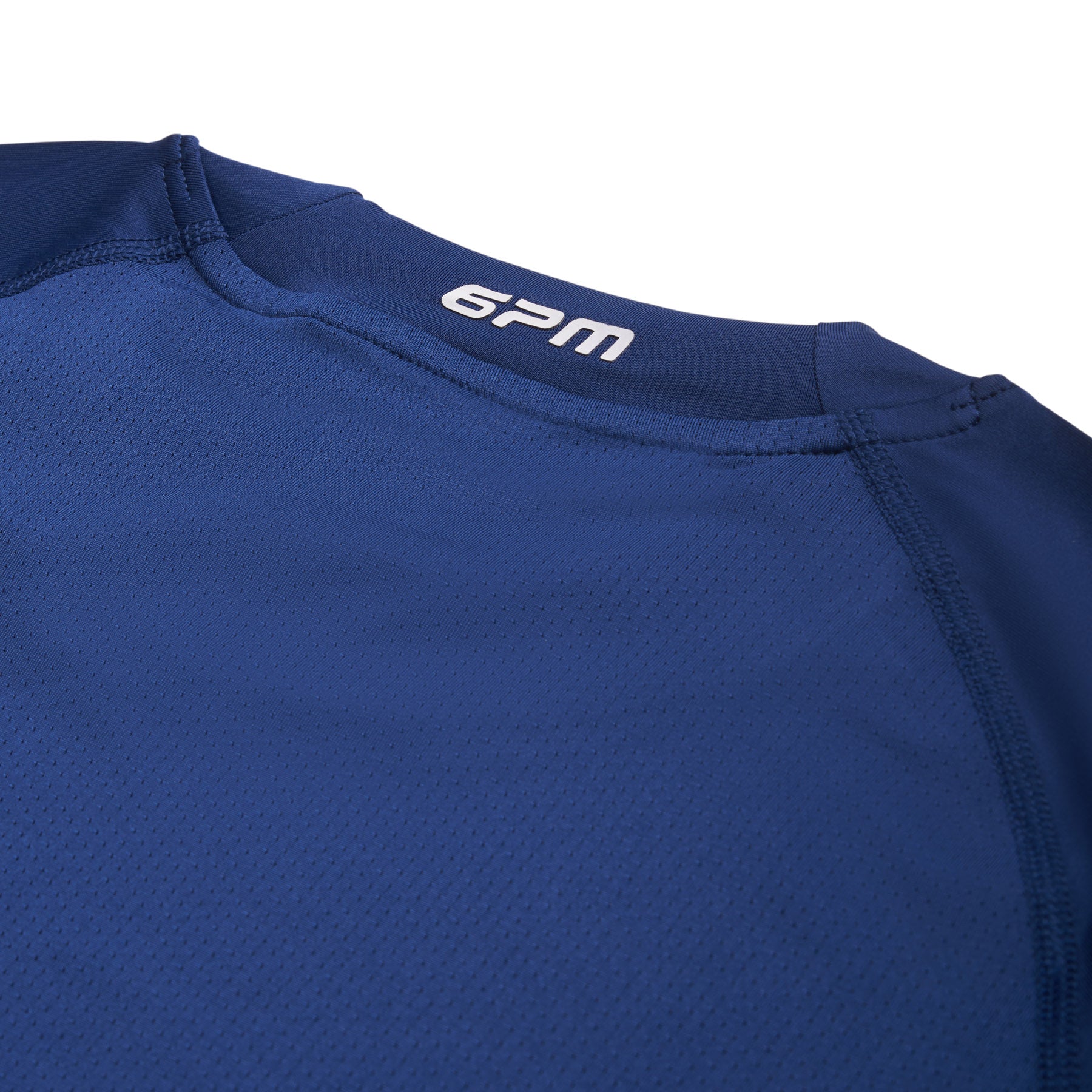 Close-up of the upper back of the 6PM SPORTS LONGSLEEVE DEEP SEA BLUE by 6PM, showing "6PM" printed in white near the collar on textured, breathable fabric with visible stitching.