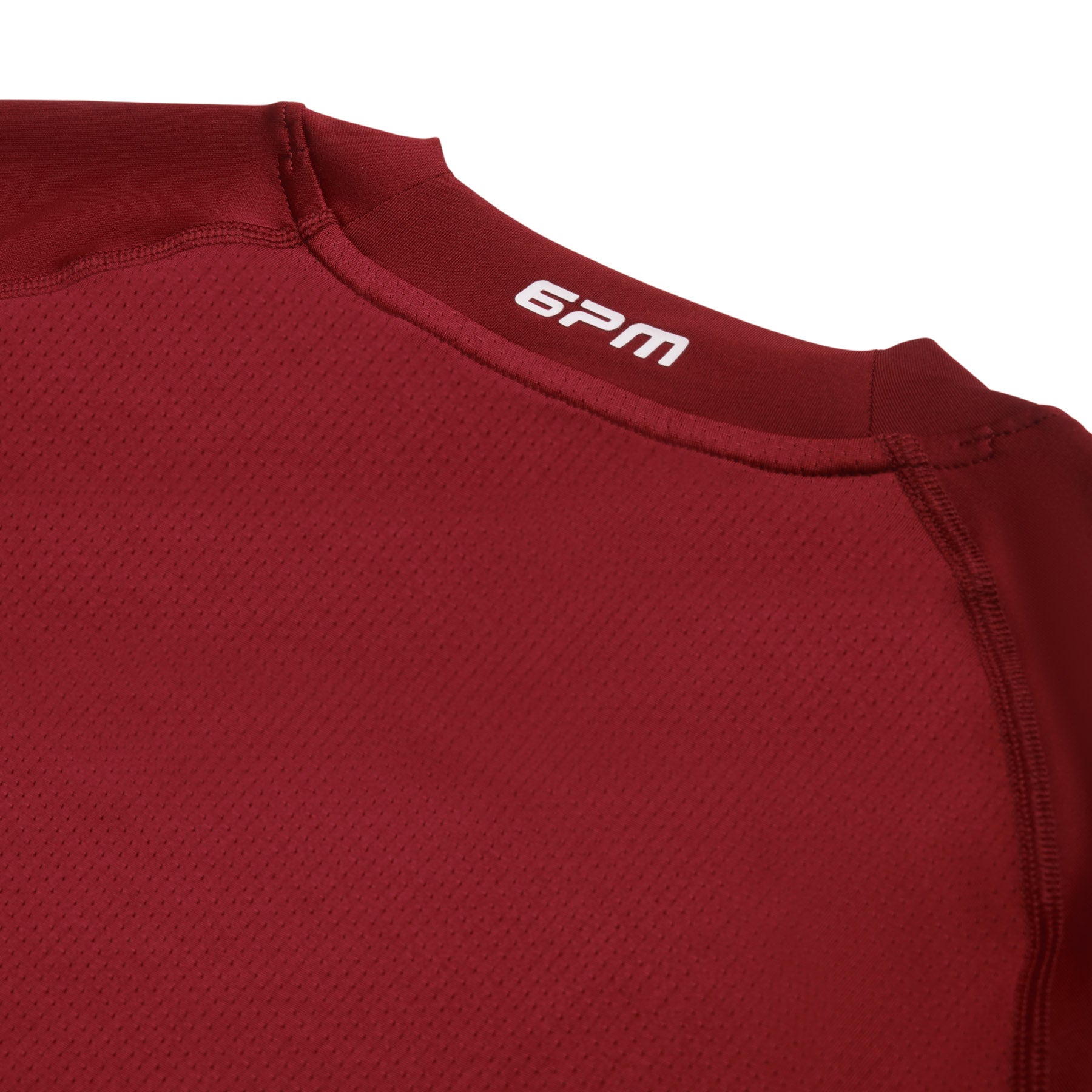 Close-up of the upper back of the 6PM SPORTS LONGSLEEVE WINE RED shirt, showing visible stitching and the white 6PM brand name near the neckline.